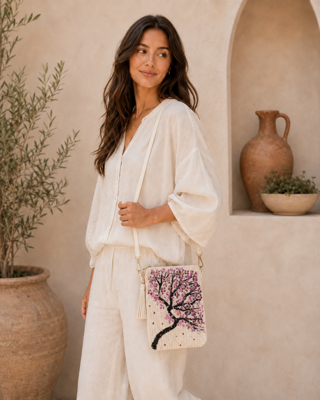 Model wearing hand-painted Cherry Blossom straw crossbody bag outdoors